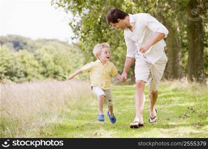 Father and son running on path holding hands smiling