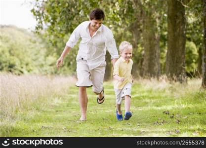 Father and son running on path smiling