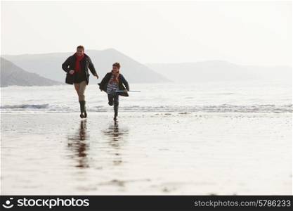 Father And Son Running On Winter Beach With Fishing Net