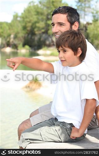 Father and son sitting by a lake