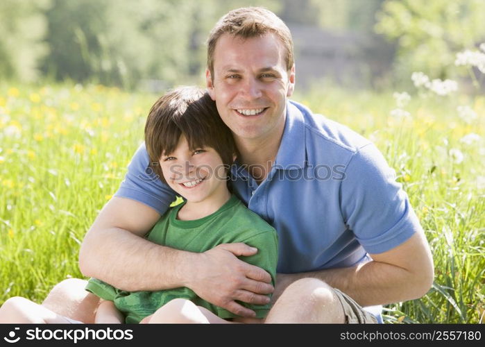 Father and son sitting outdoors smiling