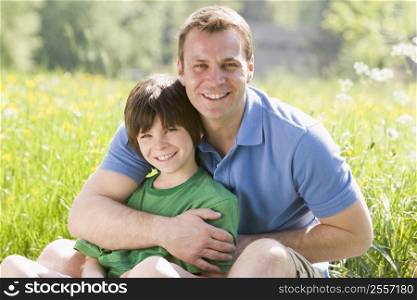 Father and son sitting outdoors smiling
