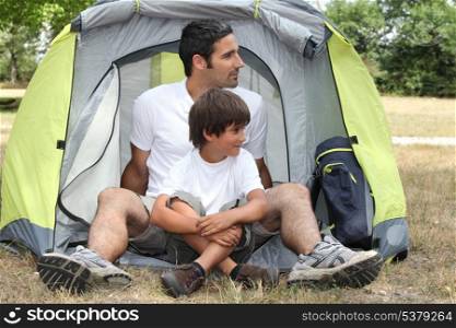 Father and son sitting outside a tent