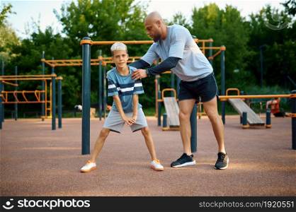 Father and son, sport training on playground outdoors. The family leads a healthy lifestyle, fitness workout in summer park. Father and son, sport training on playground