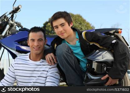 Father and son stood by motorbike