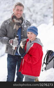 Father And Son Stopping For Hot Drink And Snack On Walk Through Snowy Landscape