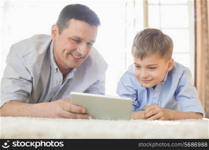 Father and son using digital table on floor at home