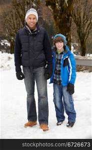 Father And Son Walking Along Snowy Street In Ski Resort