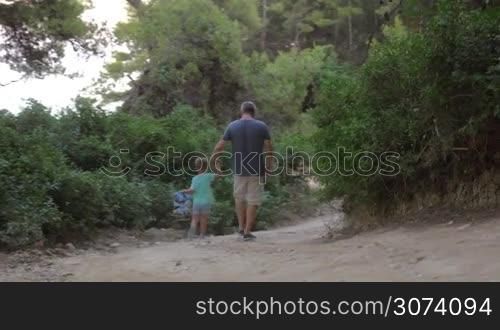 Father and son walking away in forest.Unrecognizable
