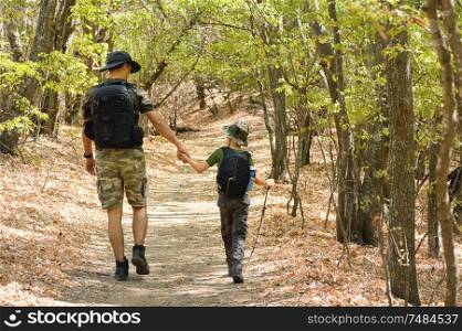 Father and son walking in autumn forest