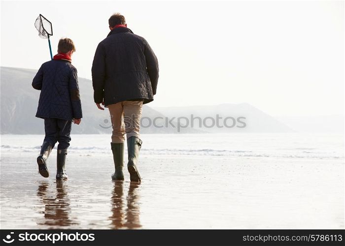 Father And Son Walking On Winter Beach With Fishing Net