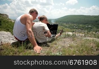 Father and son with laptop in the mountains