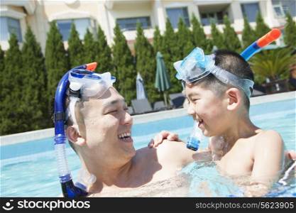 Father and son with snorkeling equipment in the pool