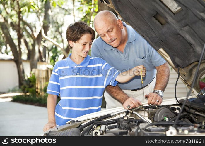 Father and son working on the car together. The son is checking the oil.