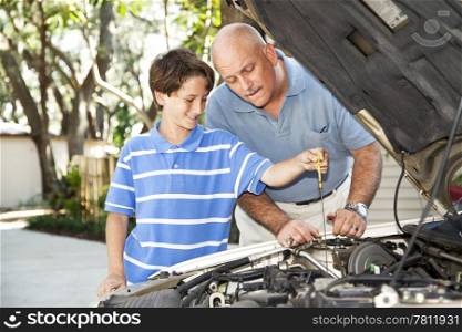 Father and son working on the car together. The son is checking the oil.