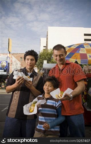 Father and sons eat hot dogs from street vendor