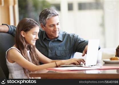 Father And Teenage Daughter Looking At Laptop Together