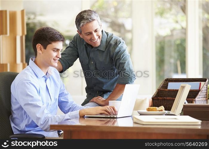 Father And Teenage Son Looking At Laptop Together