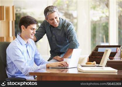 Father And Teenage Son Looking At Laptop Together