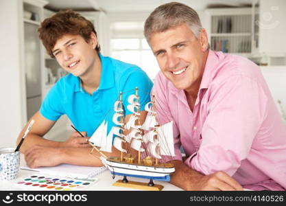 Father and teenage son model making and painting