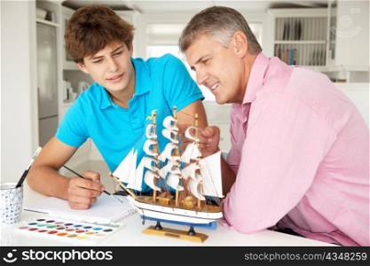 Father and teenage son model making and painting