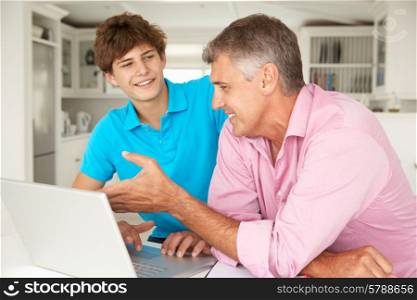 Father and teenage son using laptop