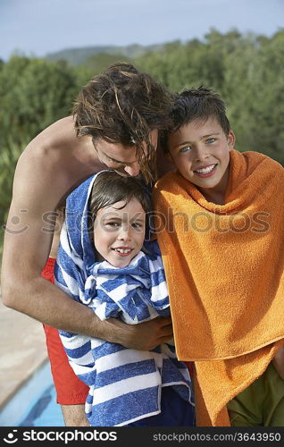 Father and two boys (6-11) wrapped in towels