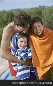 Father and two boys (6-11) wrapped in towels