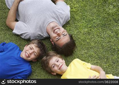 Father and two sons (6-11) lying on grass, view from above