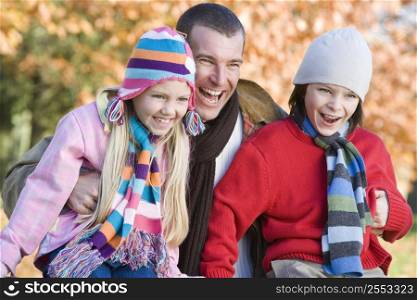 Father and two young children outdoors in park laughing (selective focus)