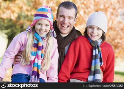 Father and two young children outdoors in park smiling (selective focus)