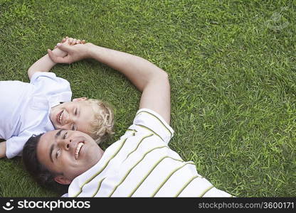 Father and young son (3-4) lying on grass, portrait