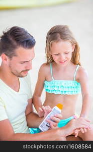 Father applying sun cream to daughter body. Young father applying sun cream to daughter on the beach. Sun protection