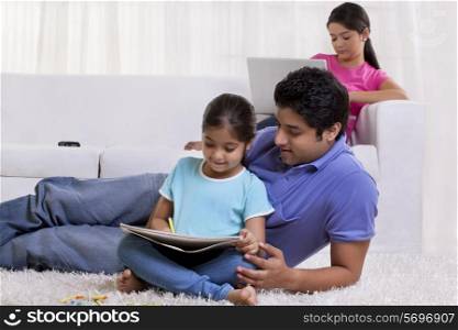 Father assisting daughter while mother working on laptop