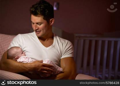Father At Home Cuddling Newborn Baby In Nursery