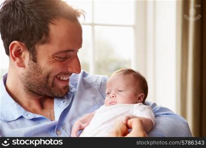 Father At Home With Newborn Baby Daughter