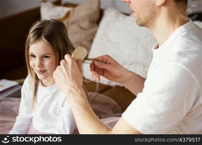 father brushing his daughter s hair