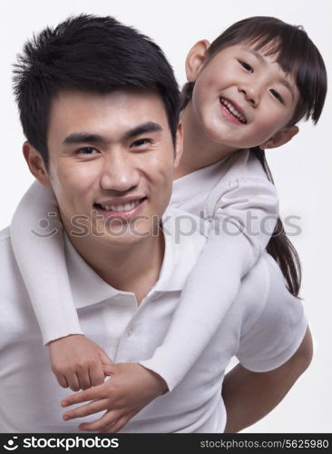 Father carrying daughter on back, studio shot