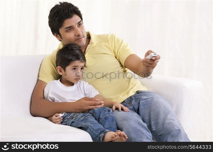 Father changing channels while sitting with his son