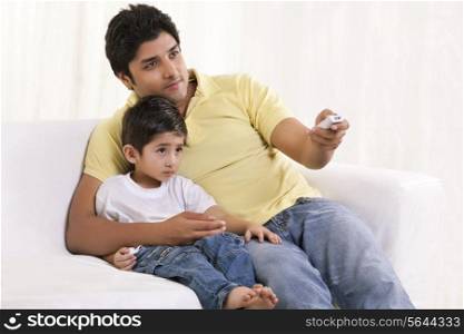 Father changing channels while sitting with his son
