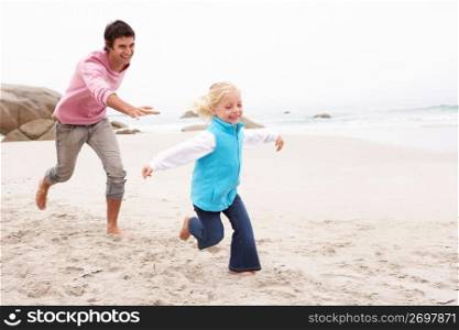 Father Chasing Daughter Along Winter Beach