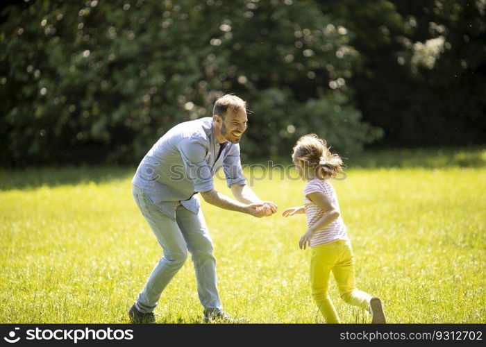 Father chasing his cute little daughter while playing in the park