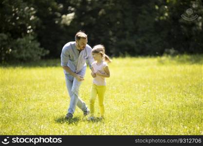 Father chasing his cute little daughter while playing in the park