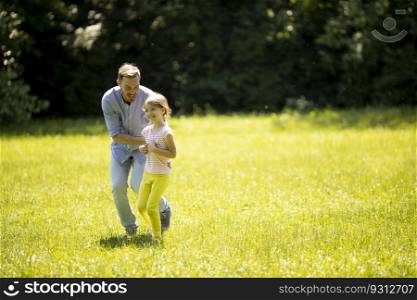 Father chasing his cute little daughter while playing in the park