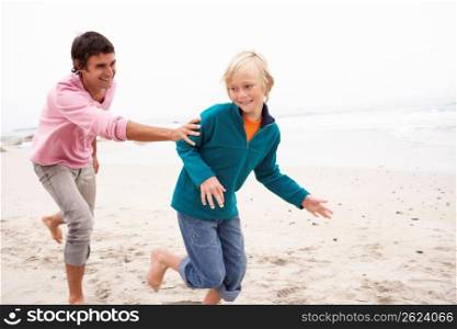 Father Chasing Son Along Winter Beach