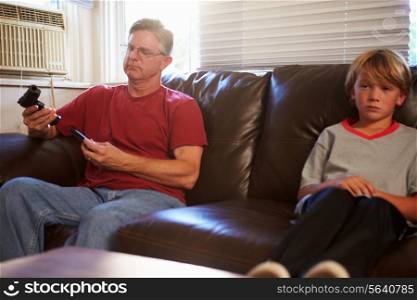 Father Checks Gun As Son Sits Next To Him On Sofa