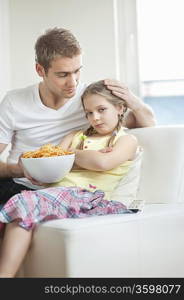 Father convincing daughter to eat wheel shape snack pellets