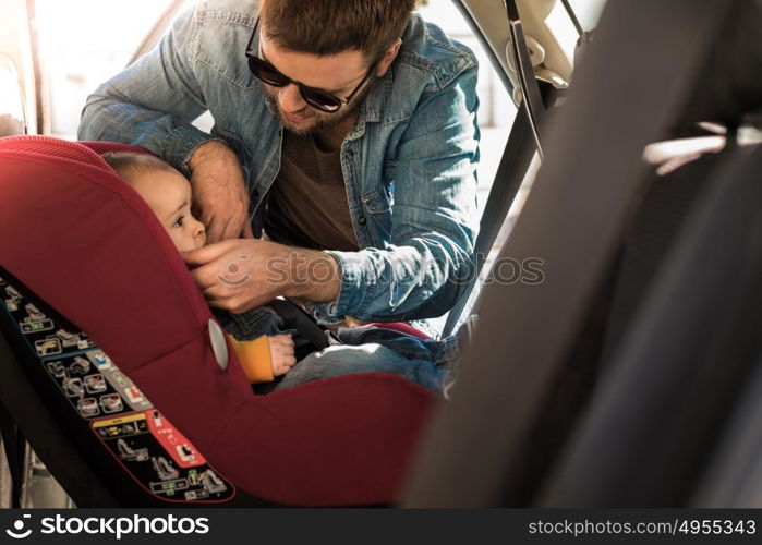 Father fasten his little baby in the car seat