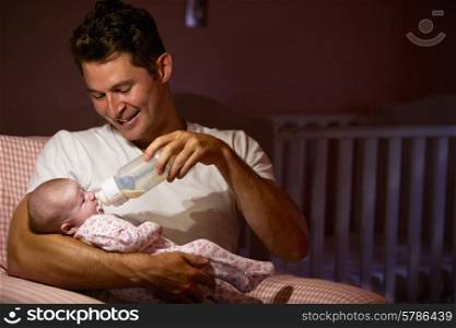 Father Feeding Baby With Bottle In Nursery
