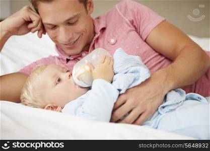 Father Giving Baby Son Bottle Of Milk